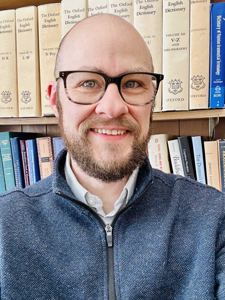 bald, bearded man wearing glasses and smiling